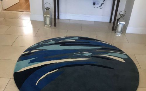 Hand tufted circular rug with splashes of blues and cream