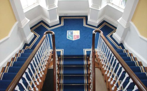 Hand tufted blue carpet with tolka border and crest on landing