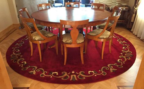 Hand tufted red circular rug with a traditional border under a dinning room table